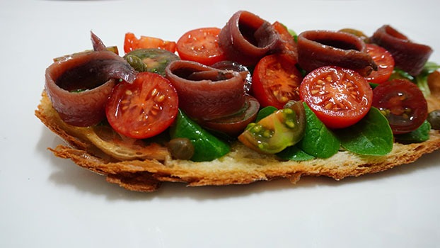 Tosta de anchoas con tomate y canónigos