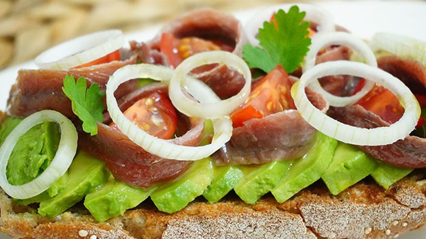 Tosta de aguacate con anchoas, tomate y cebolleta