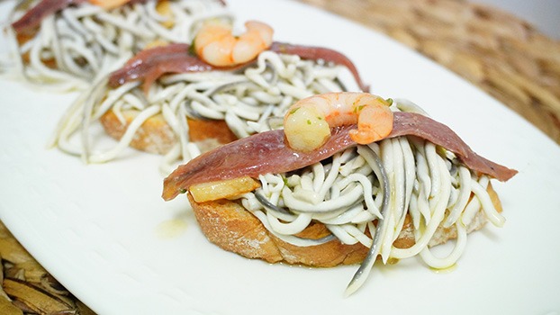 Tosta de gulas con gambas y anchoas en conserva